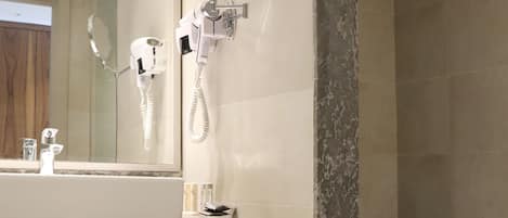 A bathroom with a marble vanity, a built-in shower, and a mirror with a round frame.