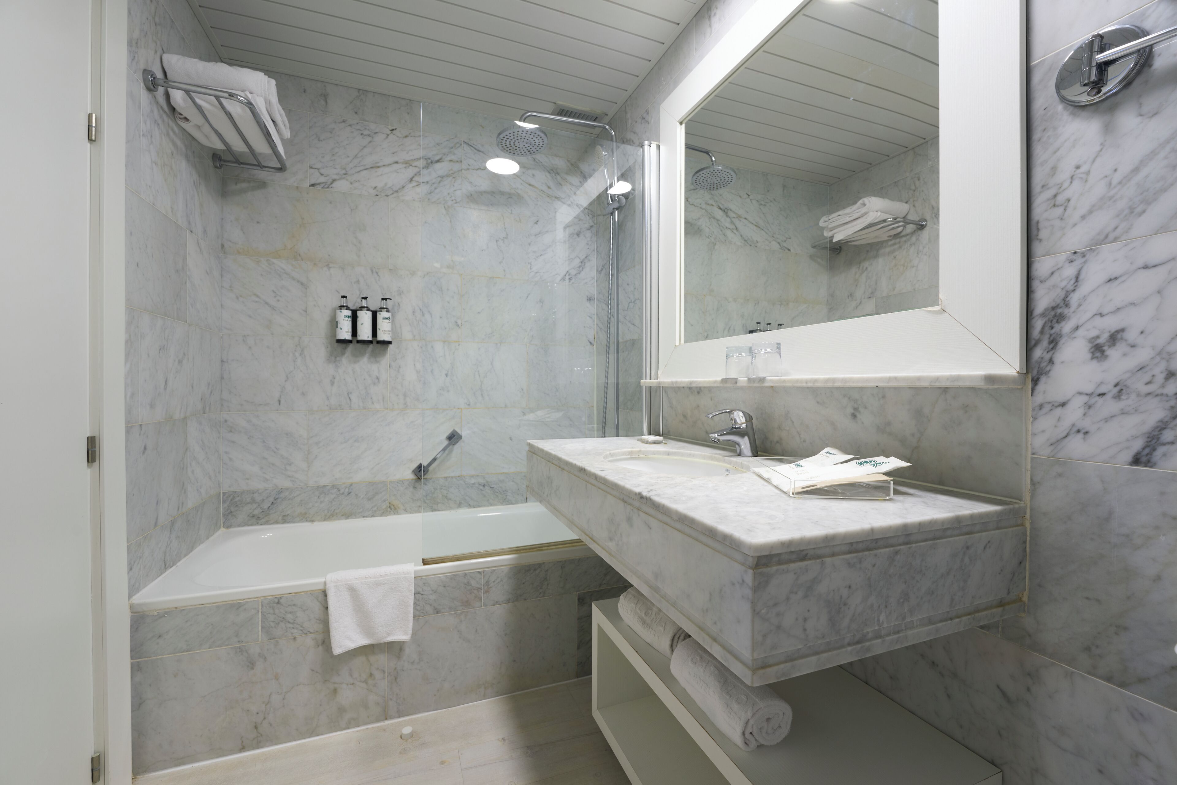 Une salle de bain moderne avec un lavabo en marbre, une baignoire et un grand miroir.