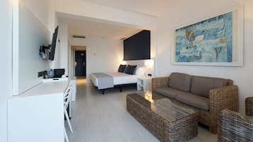 Una habitación de hotel moderna con cama, sofá, mesa de comedor y un cuadro en la pared.