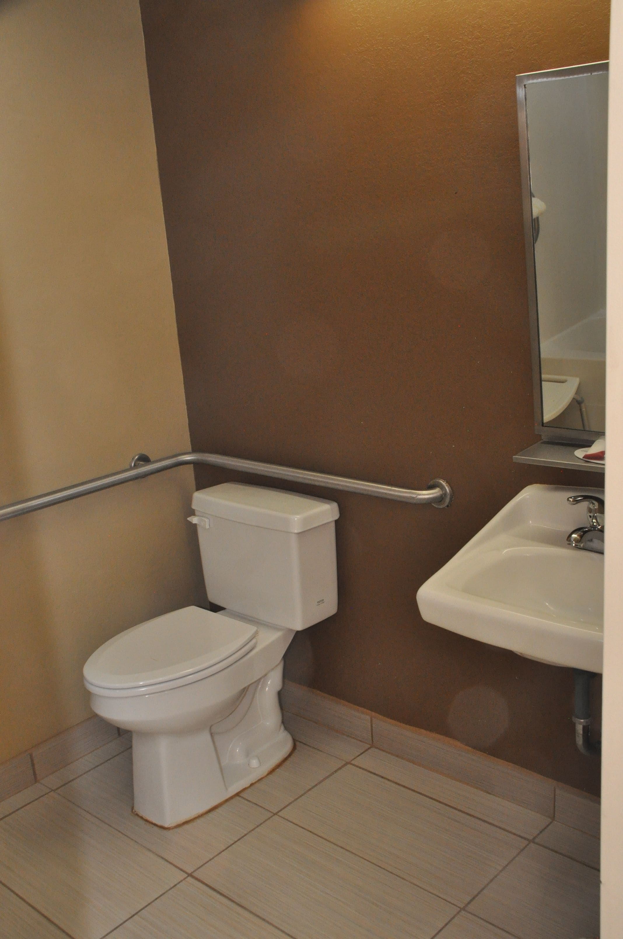 A bathroom with a white toilet, a sink, and a mirror above it.