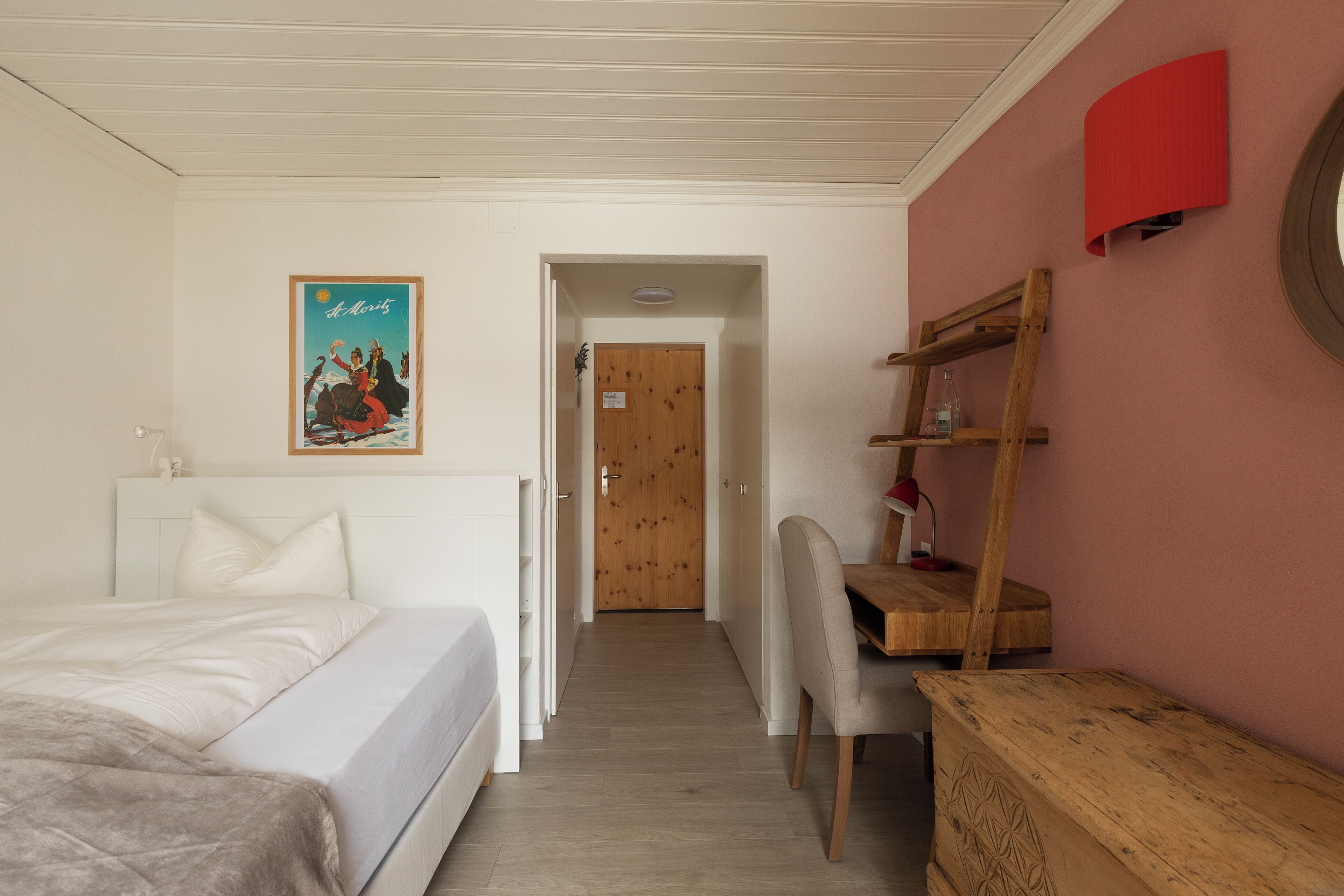 Quarto com cama, escrivaninha e cadeira.