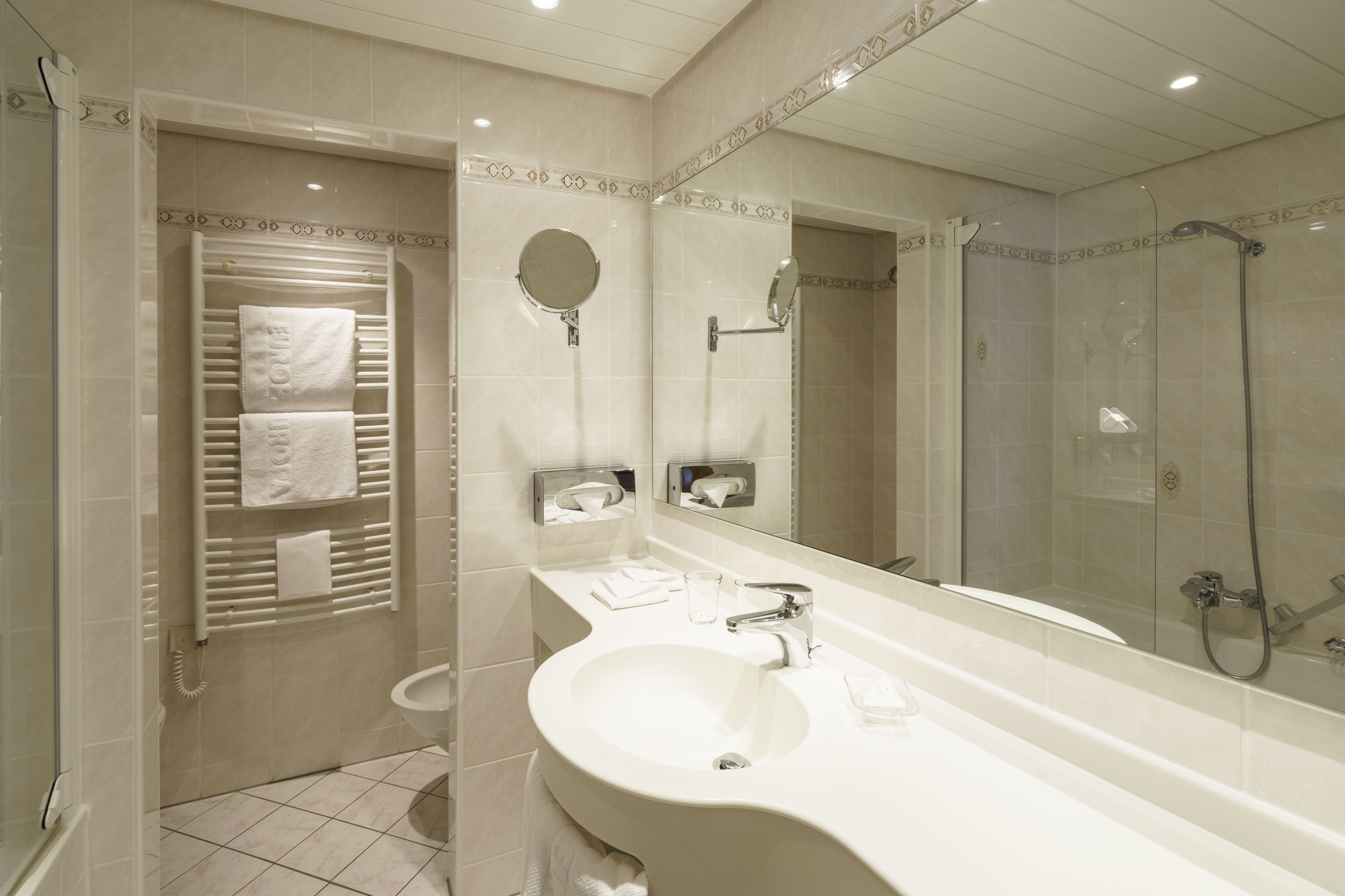 A modern bathroom with a large sink, mirror, and shower.