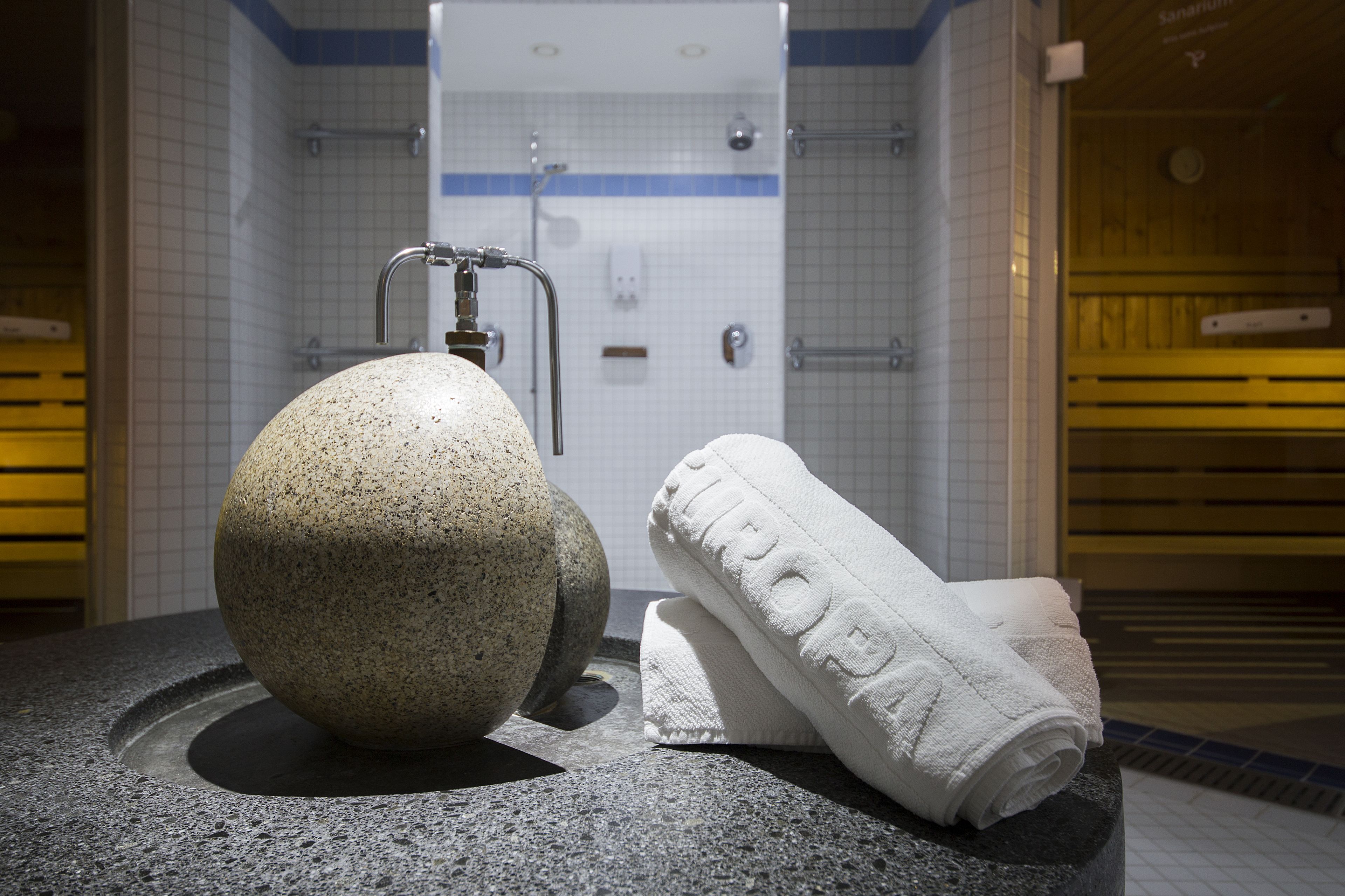 Un baño con lavabo de piedra, una toalla y zona de ducha.