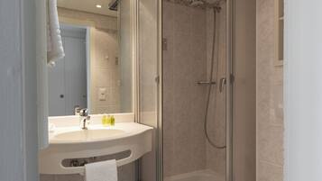 A modern bathroom with a glass-enclosed shower, a white sink, and a toilet.