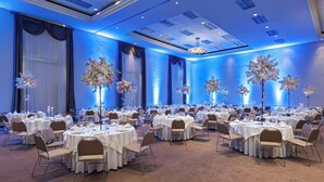 A large banquet hall with round tables, chairs, and floral centerpieces.