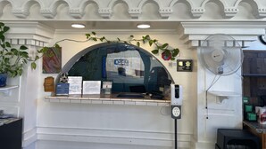 A reception area with a counter, a fan, and a sign indicating the establishment is open.