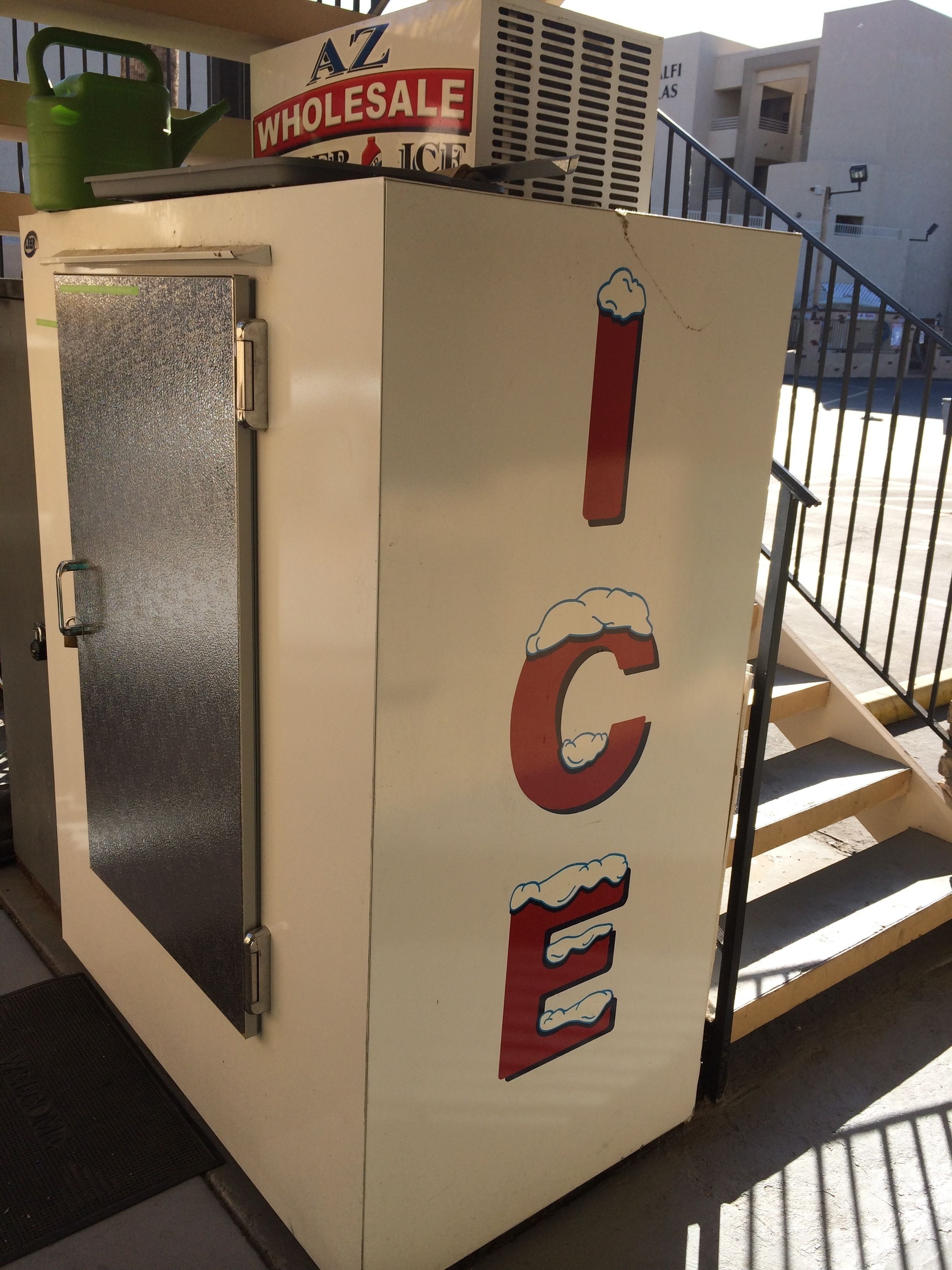A white ice cream vending machine with the words "WHOLESALE ICE" and a cartoon ice cream cone graphic.