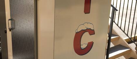 A white ice cream vending machine with the words "WHOLESALE ICE" and a cartoon ice cream cone graphic.