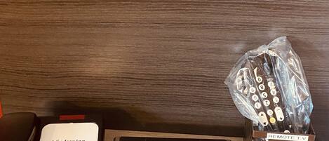 A hotel room with a remote control, a power strip, and a wall socket.