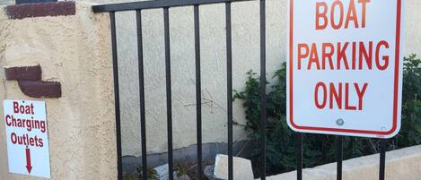 A boat charging outlet sign and a 'Boat Parking Only' sign on a fence.