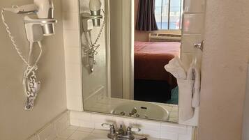 A bathroom with a sink, mirror, hairdryer, and towel rack.