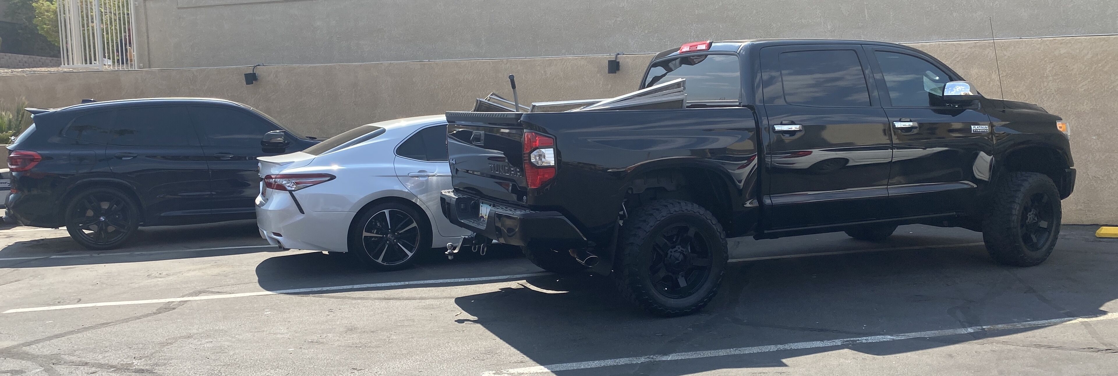 A black pickup truck parked in a lot with a white car beside it.
