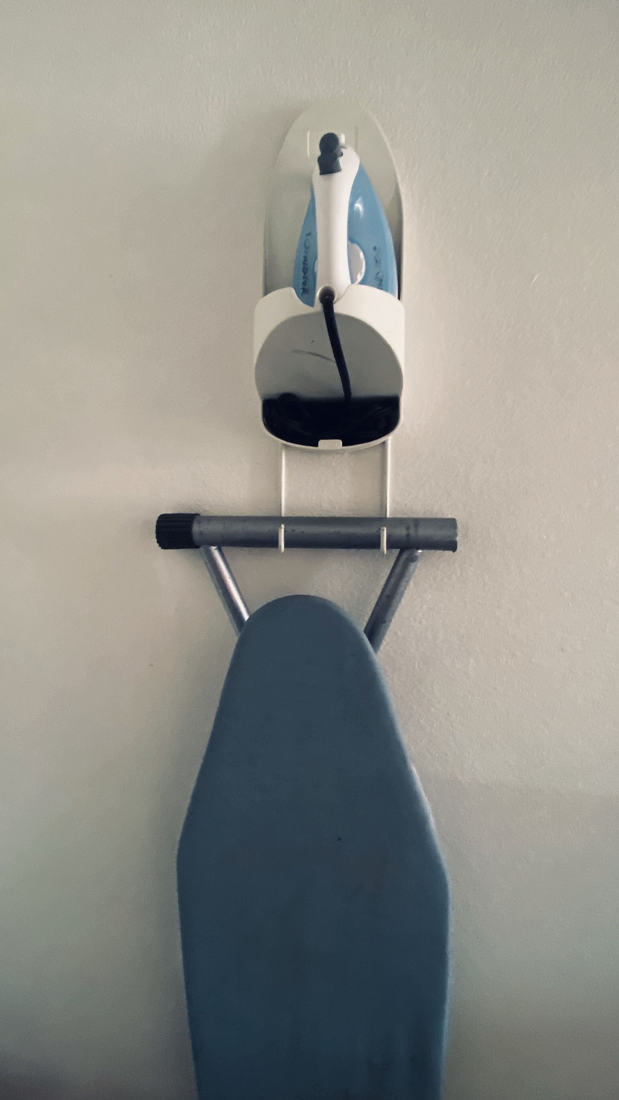 A wall-mounted ironing board with a flat surface and a metal frame.