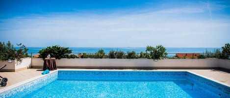 Una piscina al aire libre, sombrillas, sillones reclinables de piscina