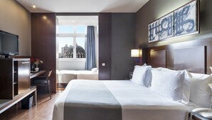 Une chambre d’hôtel avec un grand lit, un bureau, une télévision et une fenêtre avec des rideaux.