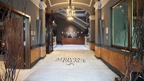 Un vaste hall d’entrée avec un comptoir de réception, un lustre et un escalier menant à un étage supérieur.