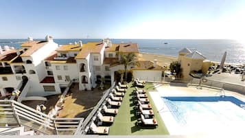 Un resort con piscina, tumbonas y vistas al mar.