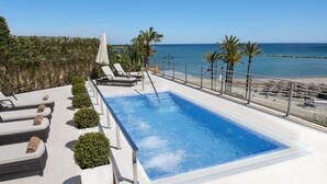 A rooftop pool with lounge chairs and a view of the beach.