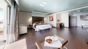 Amplia habitación de hotel con una cama grande, un escritorio y un comedor con fruteros.