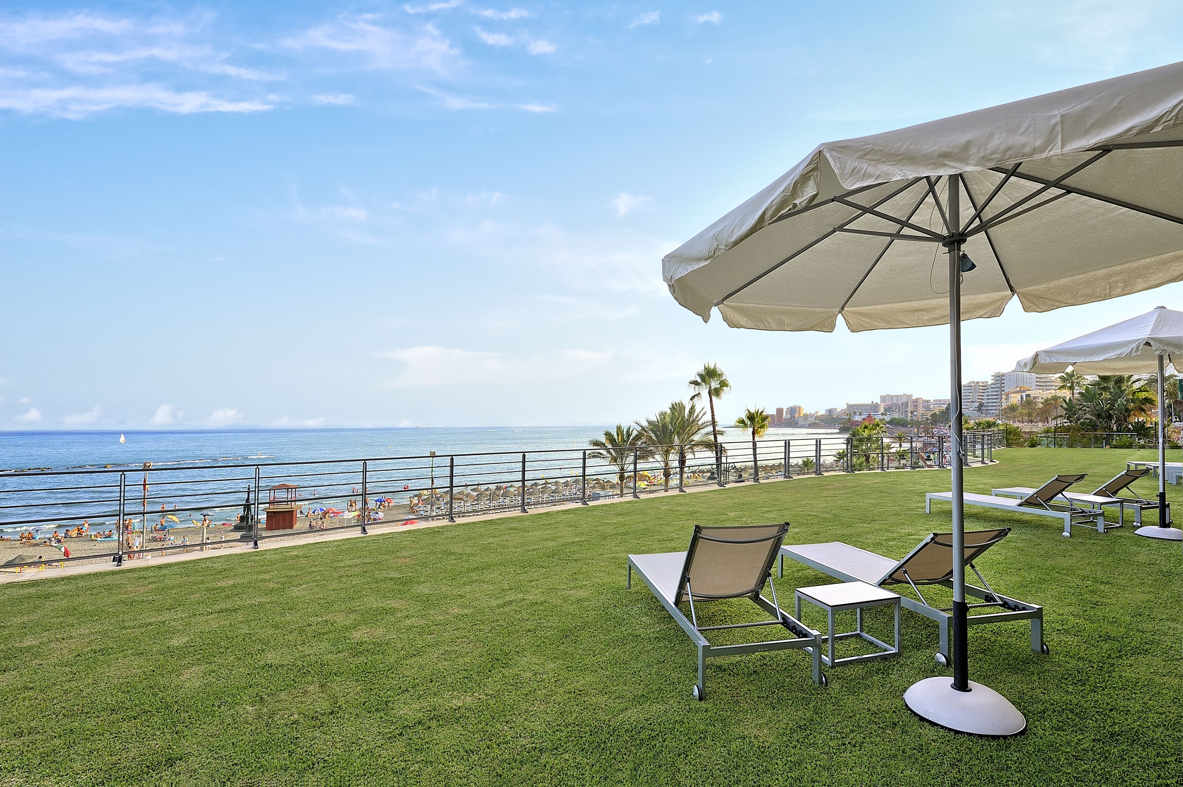 Une terrasse enherbée, dotée de chaises longues et d’un parasol, qui offre une vue sur la plage.