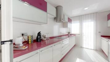 Una cocina moderna con armarios blancos, encimera roja y estufa integrada.