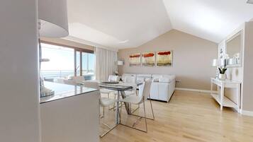Una sala de estar moderna con comedor, un conjunto de sofás y una consola decorada con objetos ornamentales.