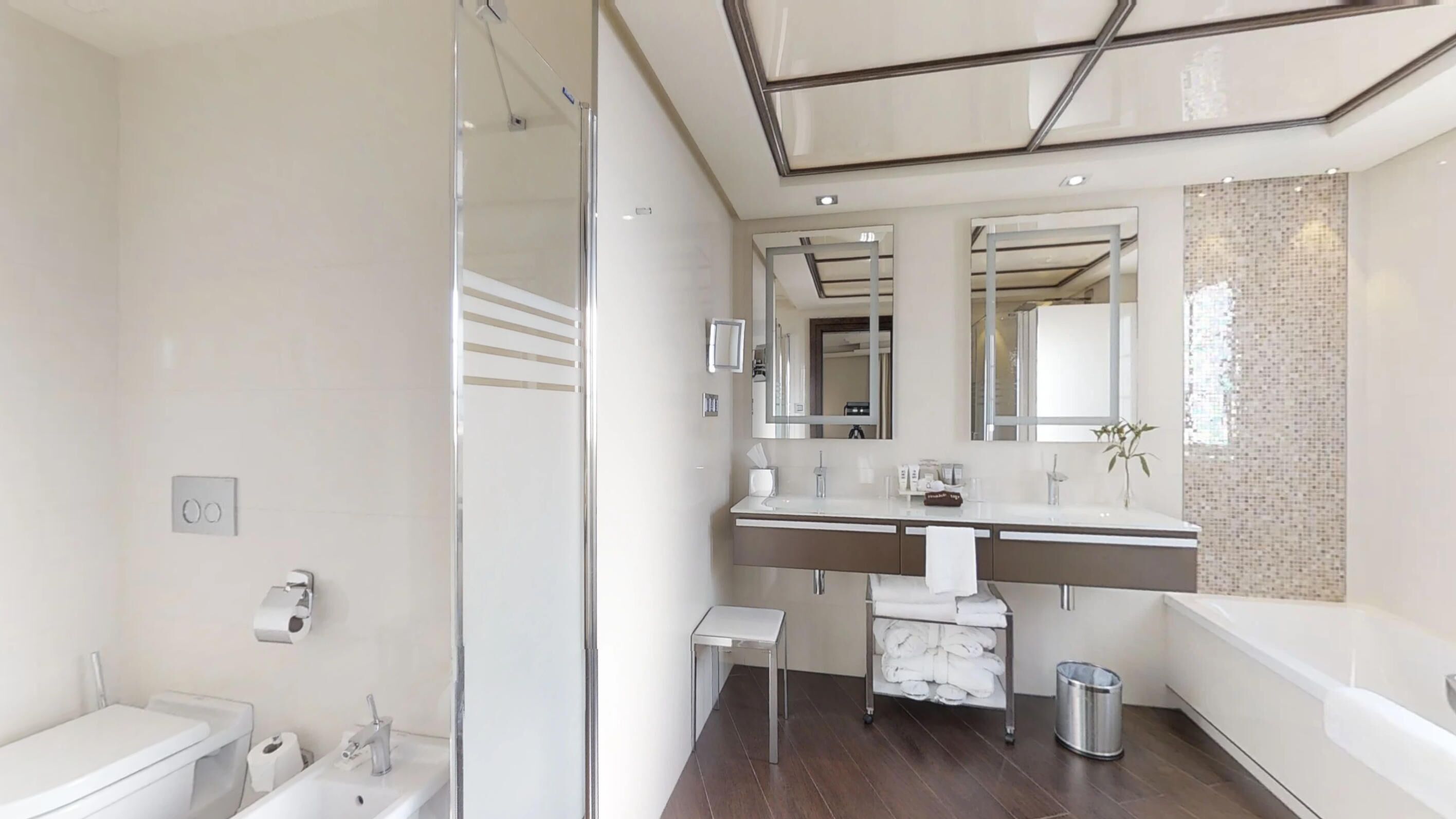 Un baño moderno con cabina de ducha de vidrio, tocador doble y un espejo grande.