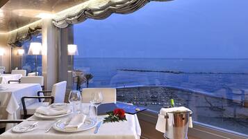 A dining table set for two with a view of the beach and ocean.