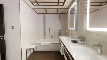 A modern bathroom with a bathtub, a large mirror, and a vanity with a sink.