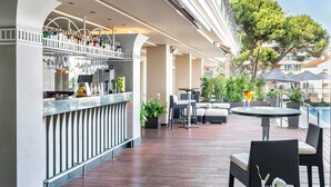 An outdoor bar area with a wooden deck, seating, and a poolside view.