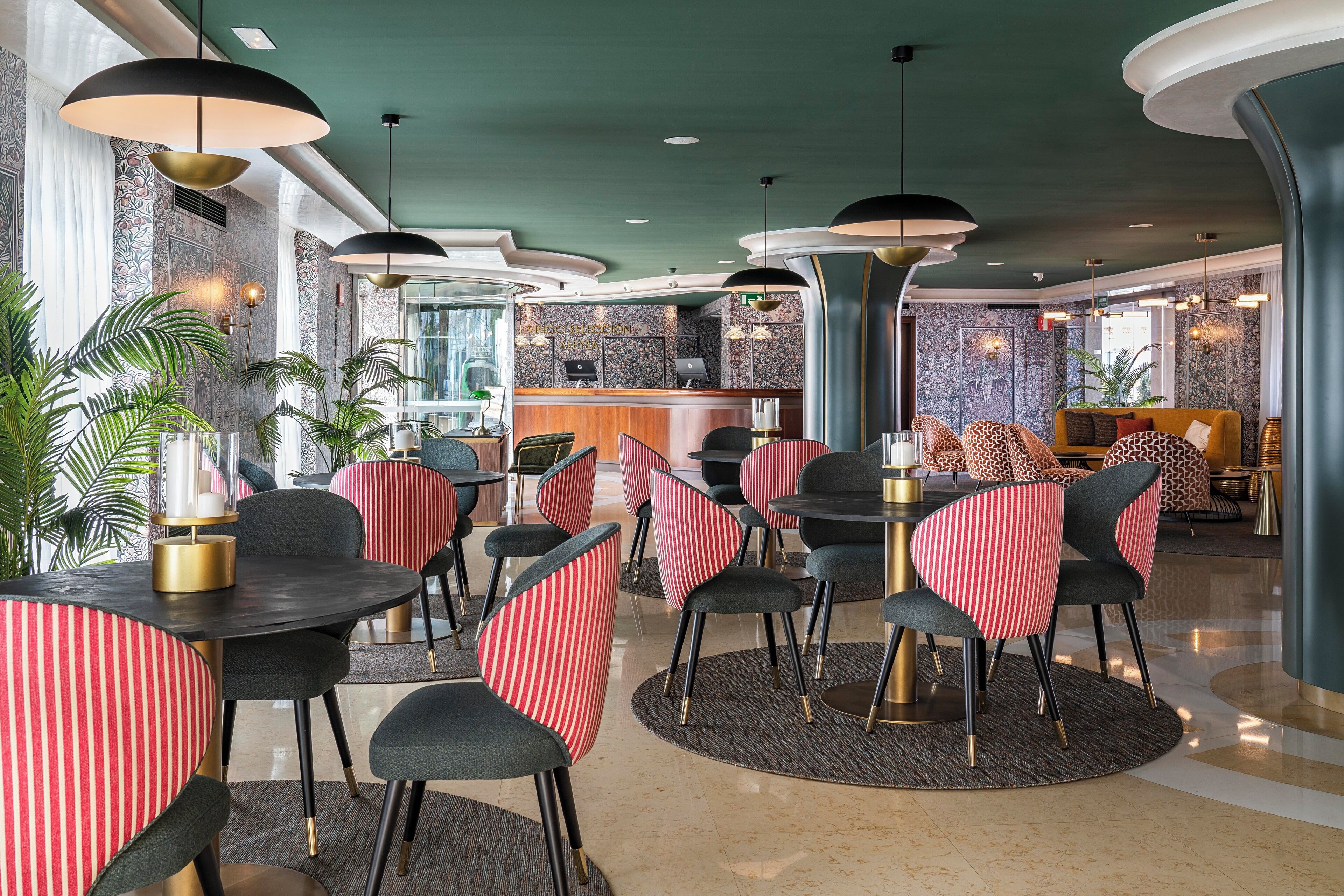A modern restaurant with round tables, striped chairs, and pendant lighting.