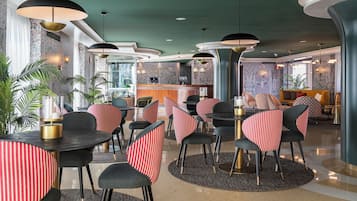 A modern restaurant with round tables, striped chairs, and pendant lighting.