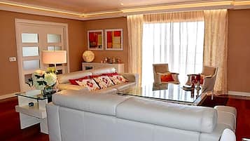 Una sala de estar moderna con un sofá blanco, una mesa de centro de vidrio y un comedor con dos sillas.