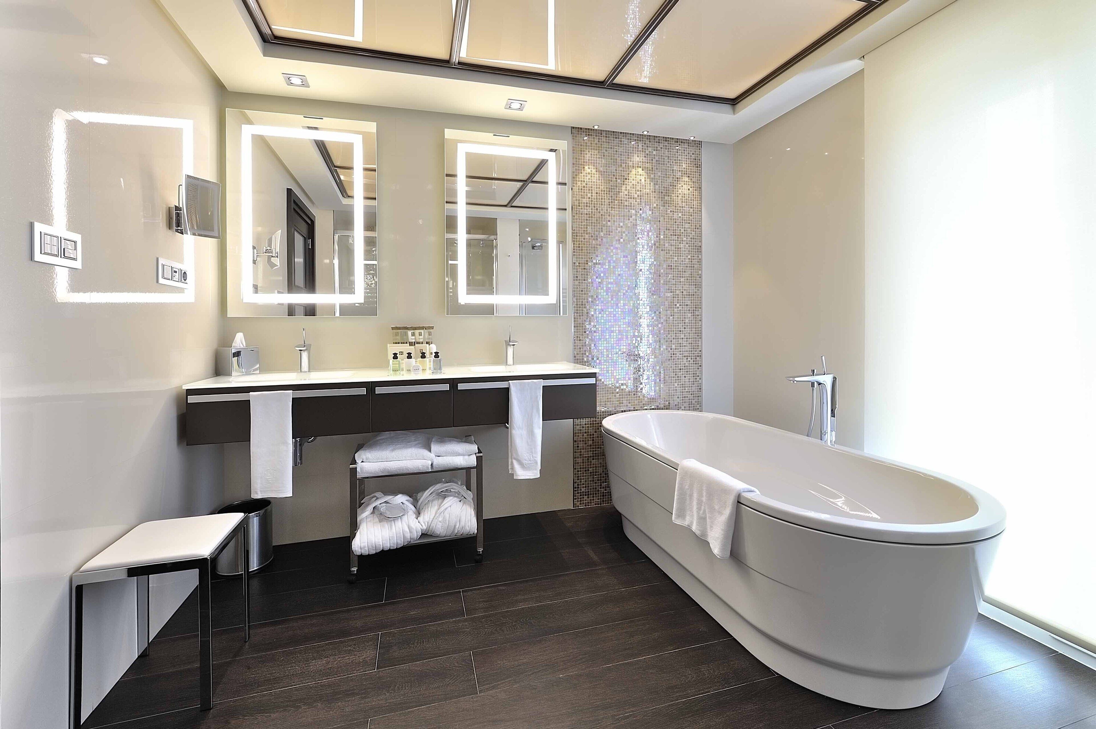 Un baño moderno con una bañera independiente, un tocador con espejo y un perchero para toallas.