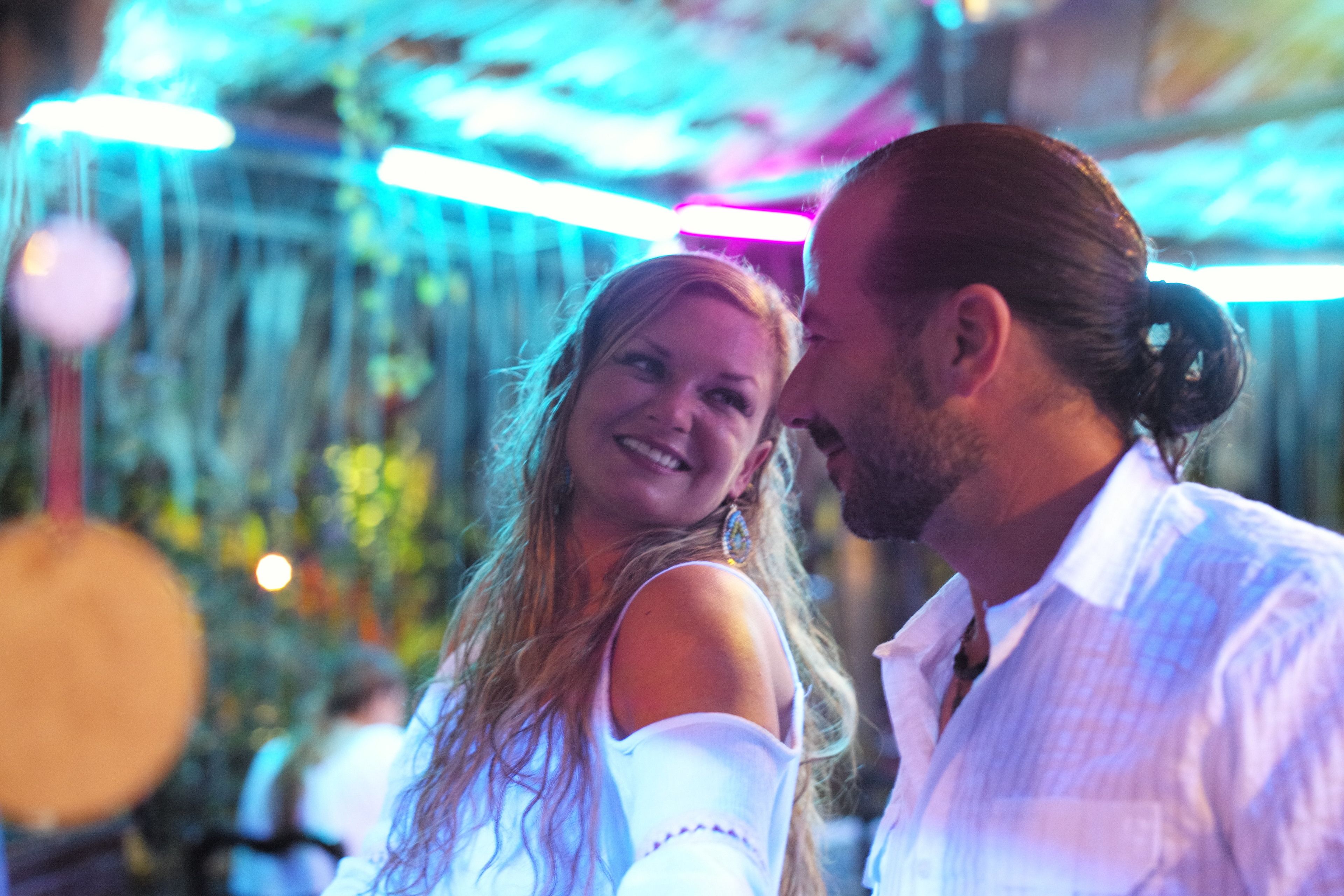 A couple in a room with a ceiling that has hanging lights and a visible window.