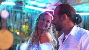 A couple in a room with a ceiling that has hanging lights and a visible window.