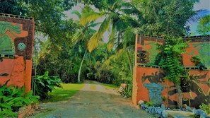Un chemin menant à un bâtiment orné d’une fresque représentant une créature verte et d’une enseigne indiquant « Belize Resort & Spa ».