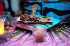 Une table à manger avec une assiette de nourriture, un verre et une bougie.