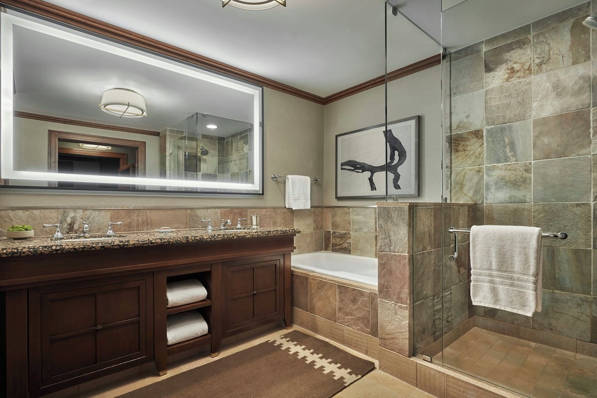 Un baño con un espejo grande, una ducha, un lavabo y un perchero para toallas.