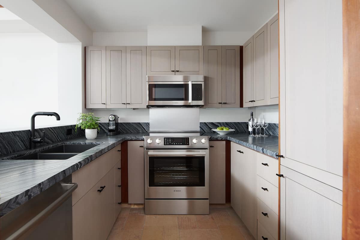 Una cocina moderna con electrodomésticos de acero inoxidable, encimera de mármol y armarios de madera.