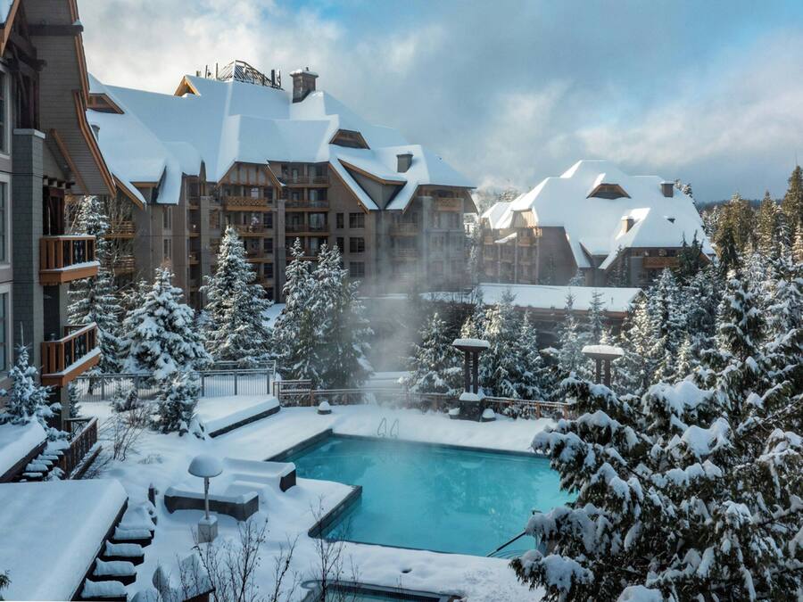 Una località turistica con piscina circondata da alberi e edifici innevati.