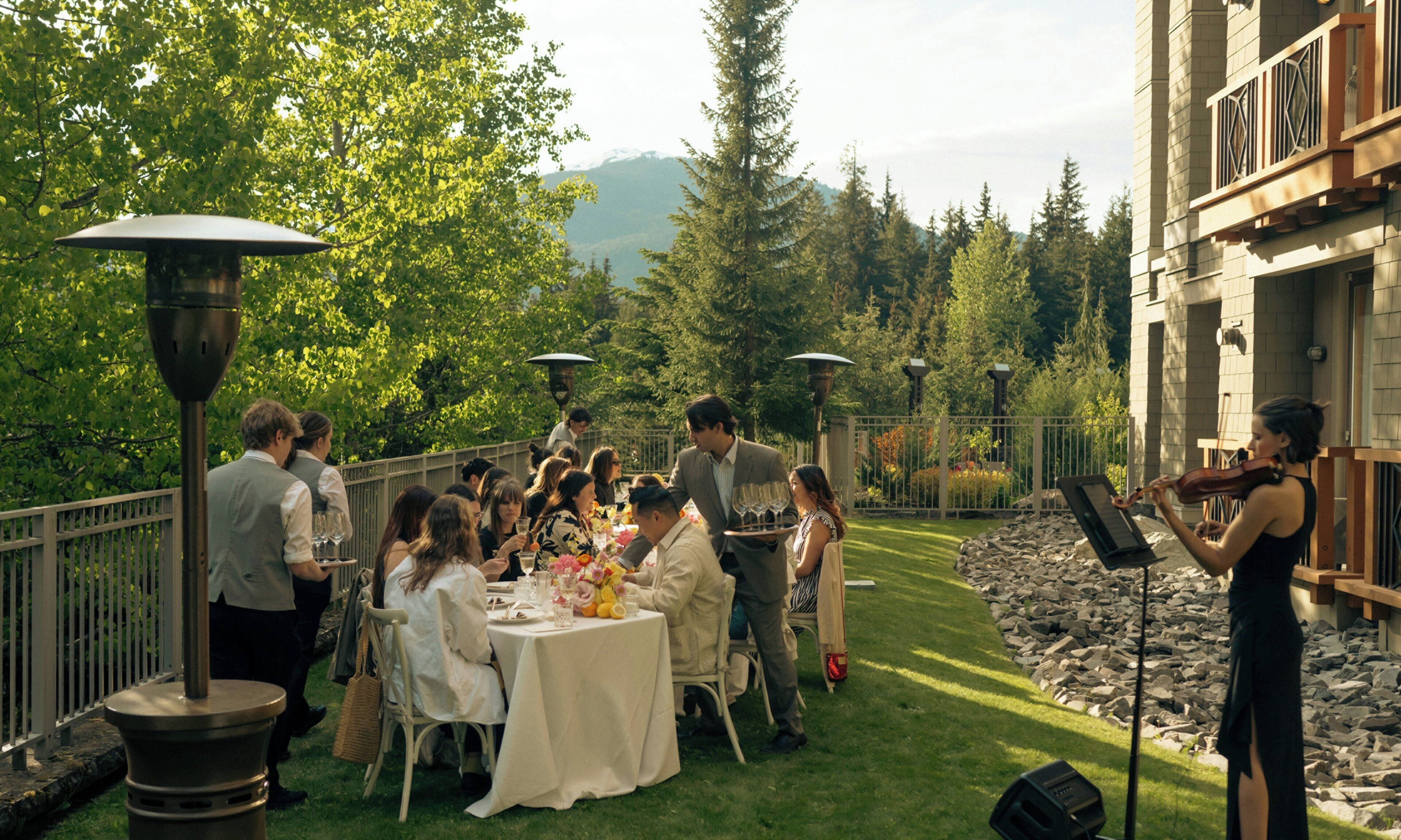 Un espacio de comedor al aire libre con mesas, sillas e invitados.