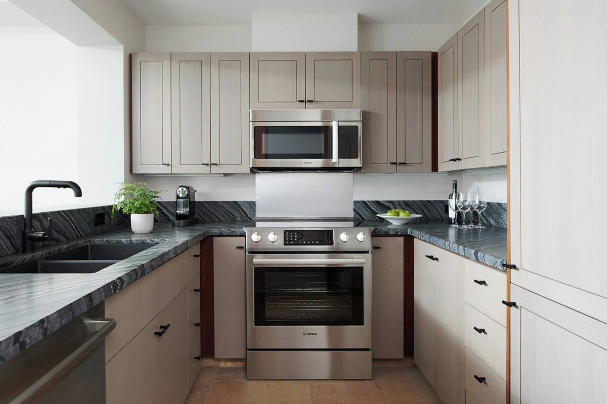 Una cocina moderna con electrodomésticos de acero inoxidable, encimera de mármol y muebles de madera clara.