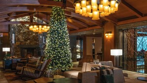Un lobby acogedor con un gran árbol de Navidad, asientos cómodos y una chimenea de piedra.