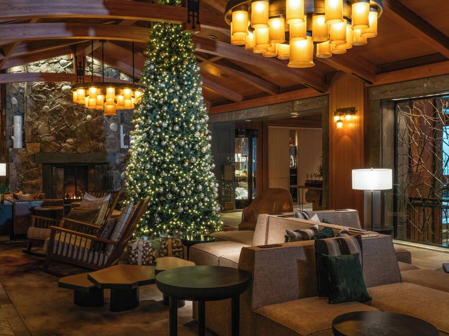 A cozy lobby with a large Christmas tree, comfortable seating, and a stone fireplace.