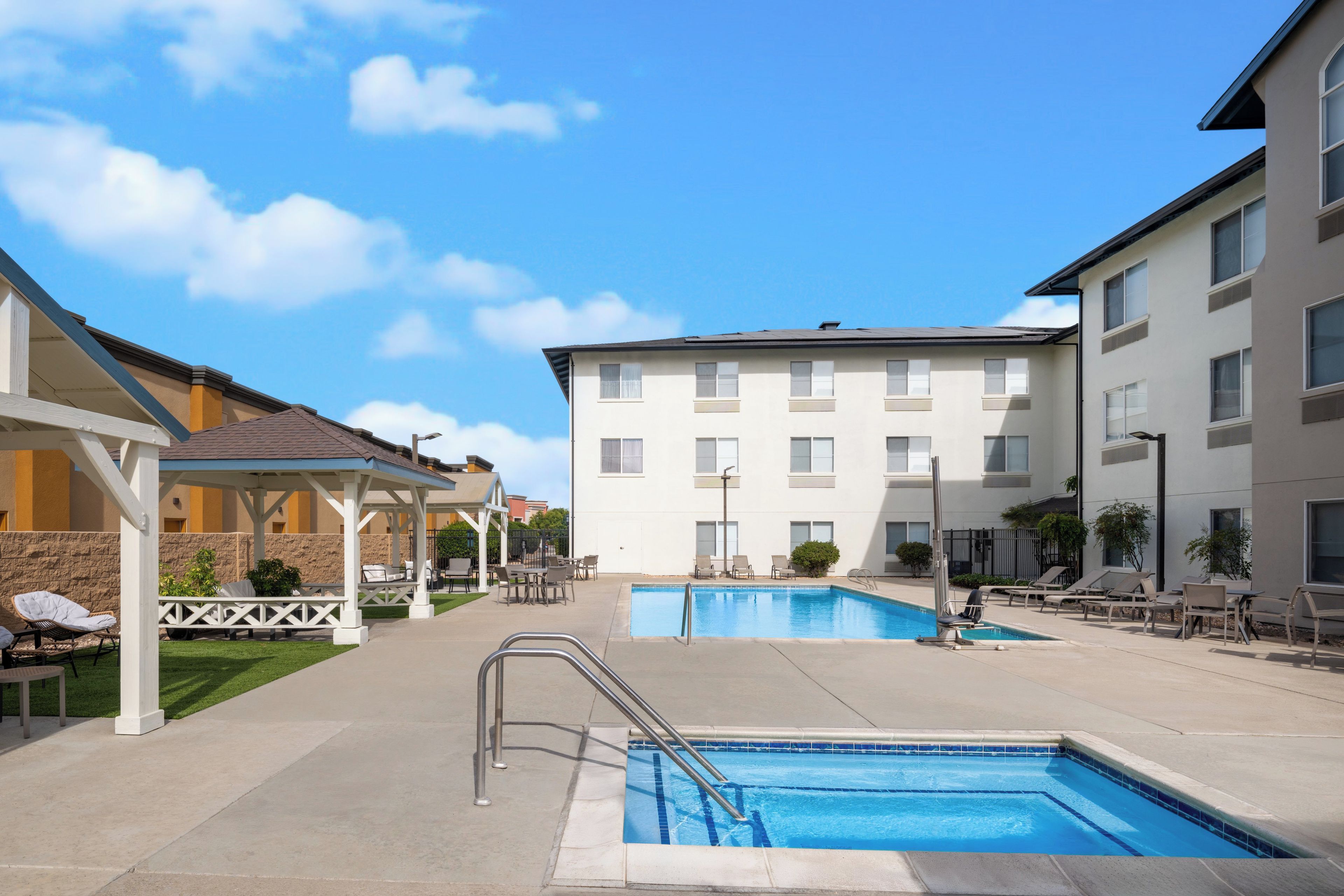 A swimming pool area with lounge chairs and a covered seating area.