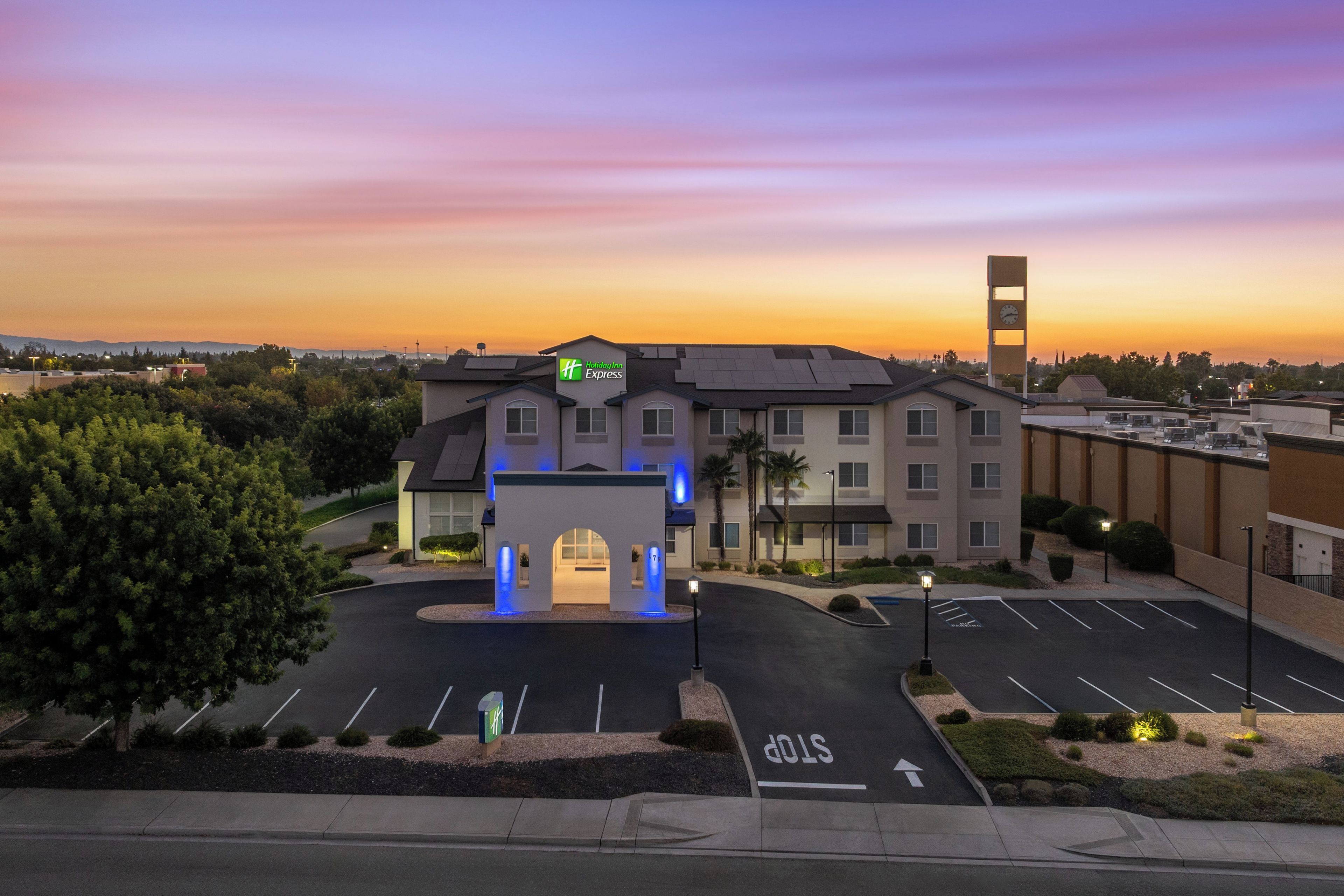 A Holiday Inn Express hotel with a parking lot, a stop sign, and a clock tower.