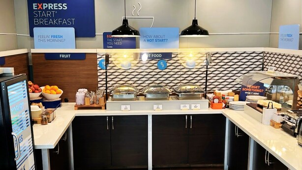 A breakfast buffet area with labeled food stations, a fruit section, and a sign asking about the start of the day. - Holiday Inn Express Hotel & Suites Manteca by IHG (Manteca)