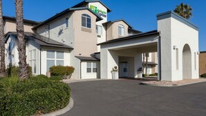 A Holiday Inn Express hotel with a modern design, featuring a covered entrance and palm trees in the landscaping. - Holiday Inn Express Hotel & Suites Manteca by IHG (Manteca)