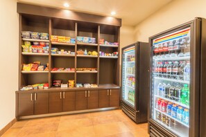 Un espace de vente en libre-service proposant des collations et des boissons, avec plusieurs étagères remplies de divers produits.